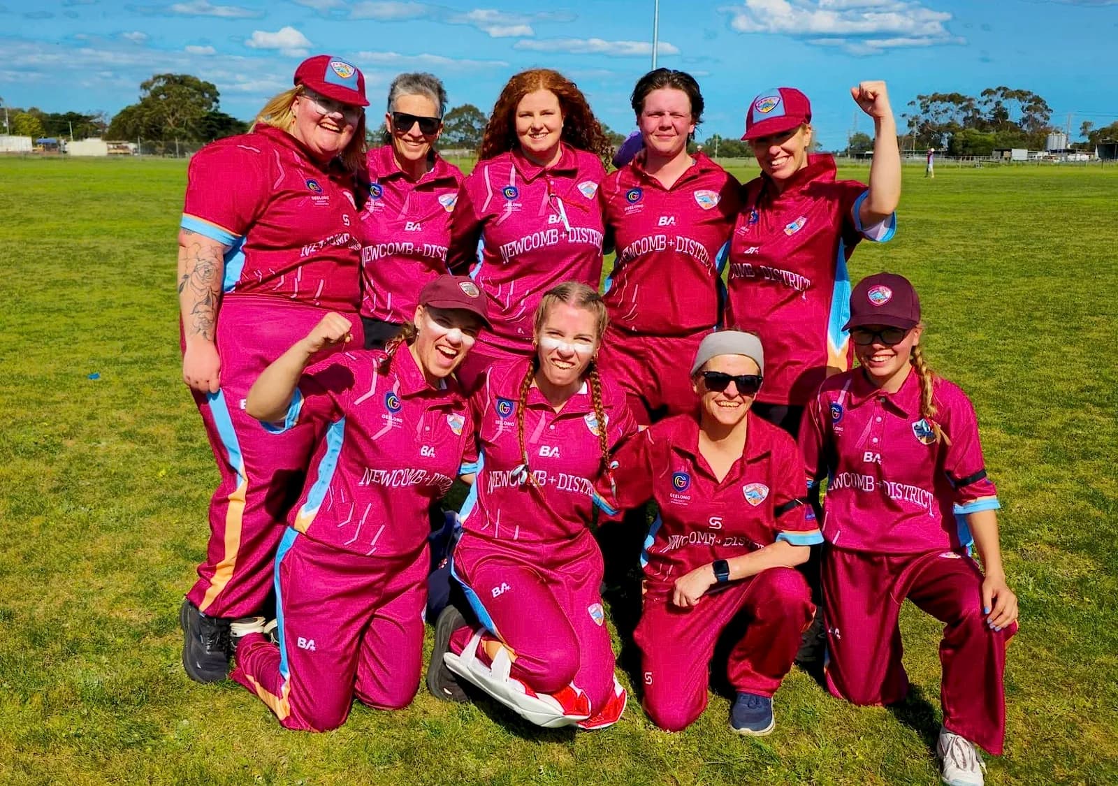 Newcomb & District women's team celebrating on the ground, some players with fists raised